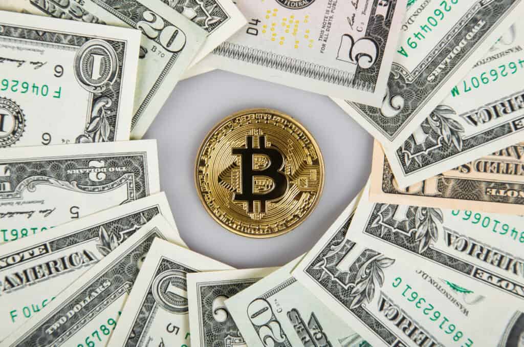 gold bitcoin surrounded by dollar bills