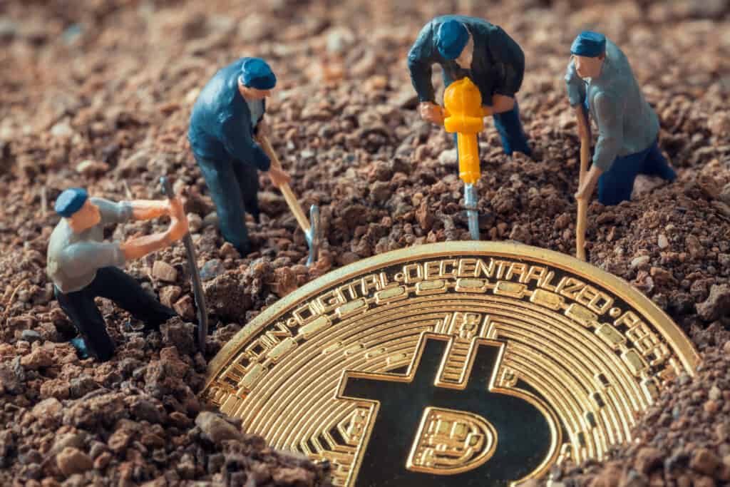 miner figurines digging ground to uncover bitcoin