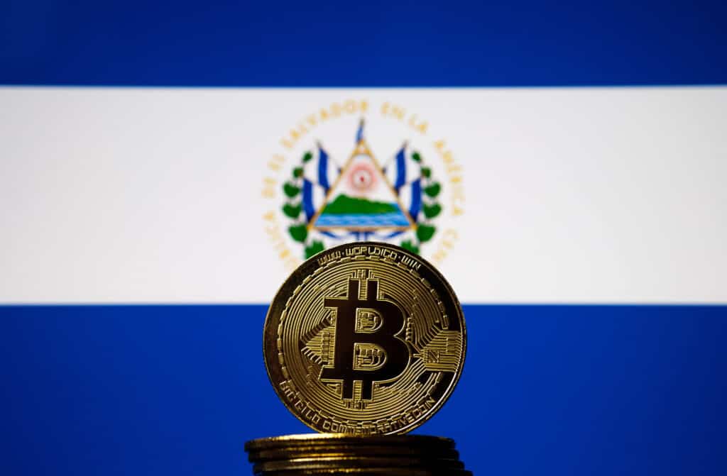 Bitcoin representation coin placed in front of blurred Salvador's national flag. El Salvador is the first country to adopt bitcoin as legal tender. Concept.