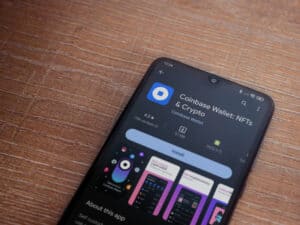 Coinbase Wallet app play store page on smartphone on wooden background. Top view flat lay with copy space.