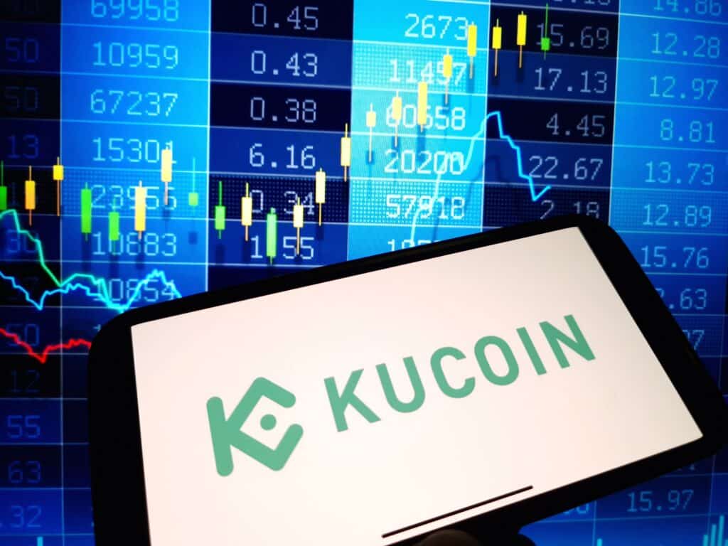 KuCoin cryptocurrency exchange logo displayed on smartphone on crypto market data background