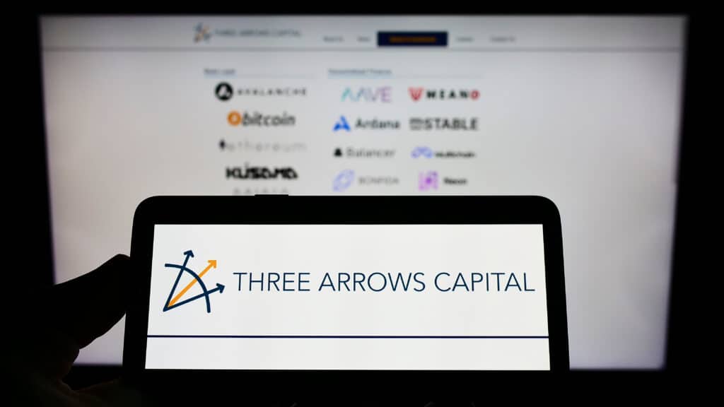 Person holding mobile phone with logo of US investment company Three Arrows Capital Ltd. on screen in front of web page.