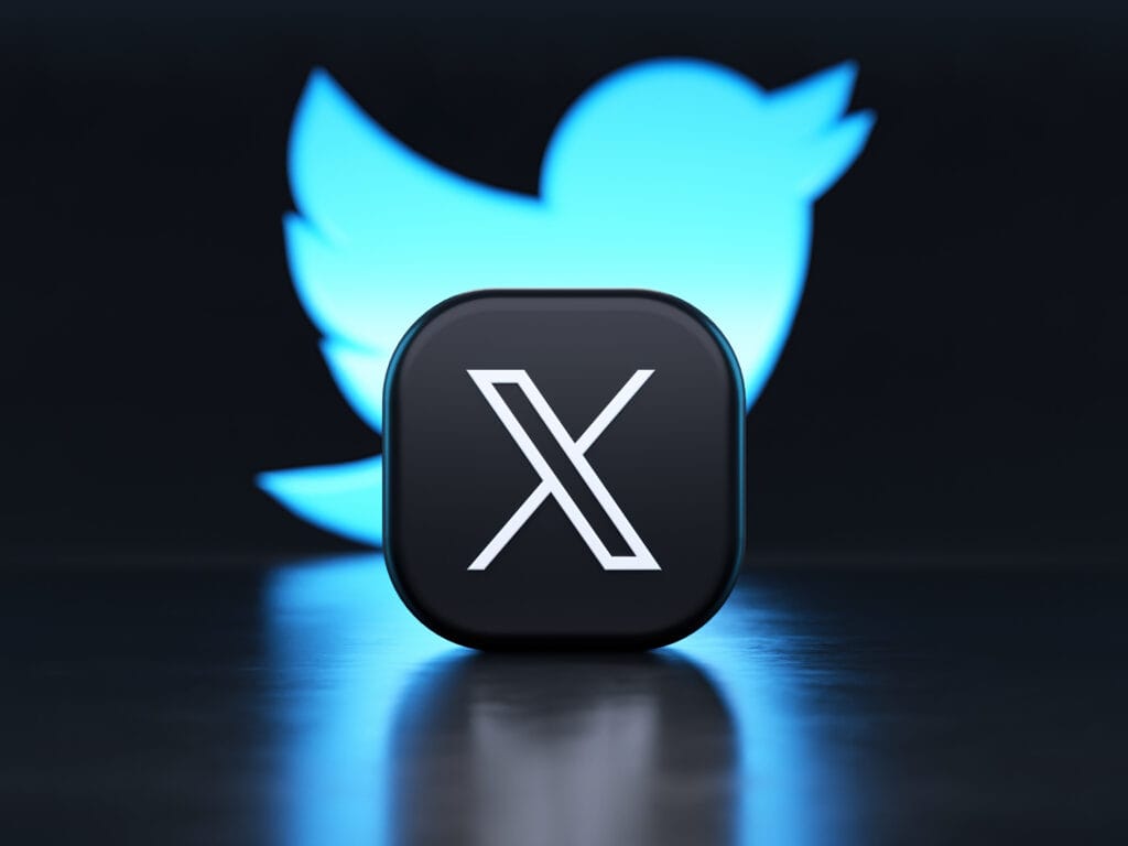 X app logo in front of the Twitter blue bird symbol background in 3D rendering.