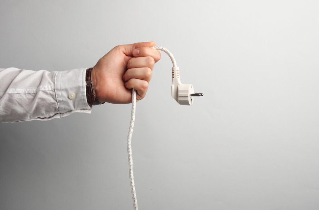 Man's hand in white shirt holds electrical plug