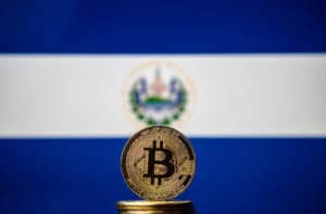 Bitcoin representation coin placed in front of blurred Salvador's national flag.