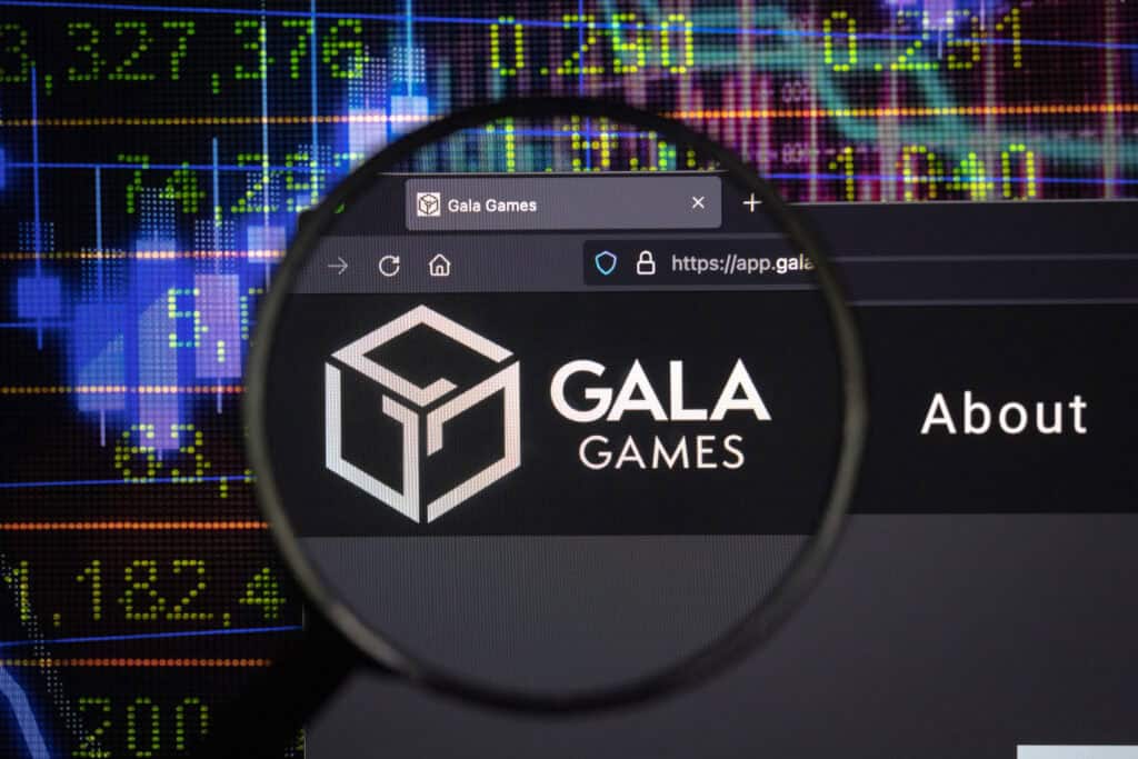 Gala crypto company logo on a website, seen on a computer screen through a magnifying glass.
