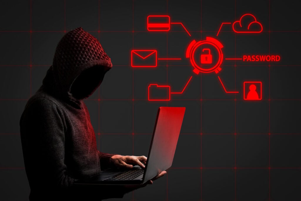 Faceless man in a hoodie with a hood holds a laptop in his hands