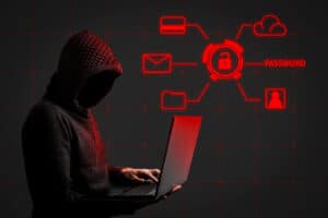 Faceless man in a hoodie with a hood holds a laptop in his hands
