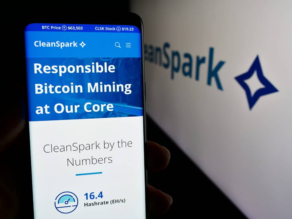 Person holding smartphone with web page of US Bitcoin mining company CleanSpark Inc. in front of logo. Source: Timon - stock.adobe.com