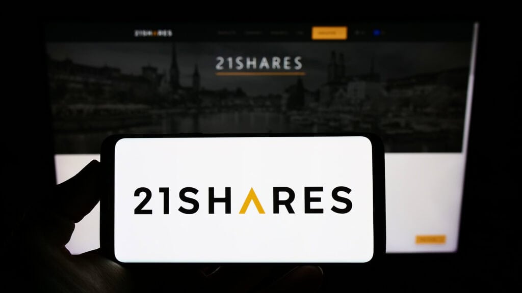 Person holding smartphone with logo of Swiss crypto company 21Shares AG on screen in front of website.