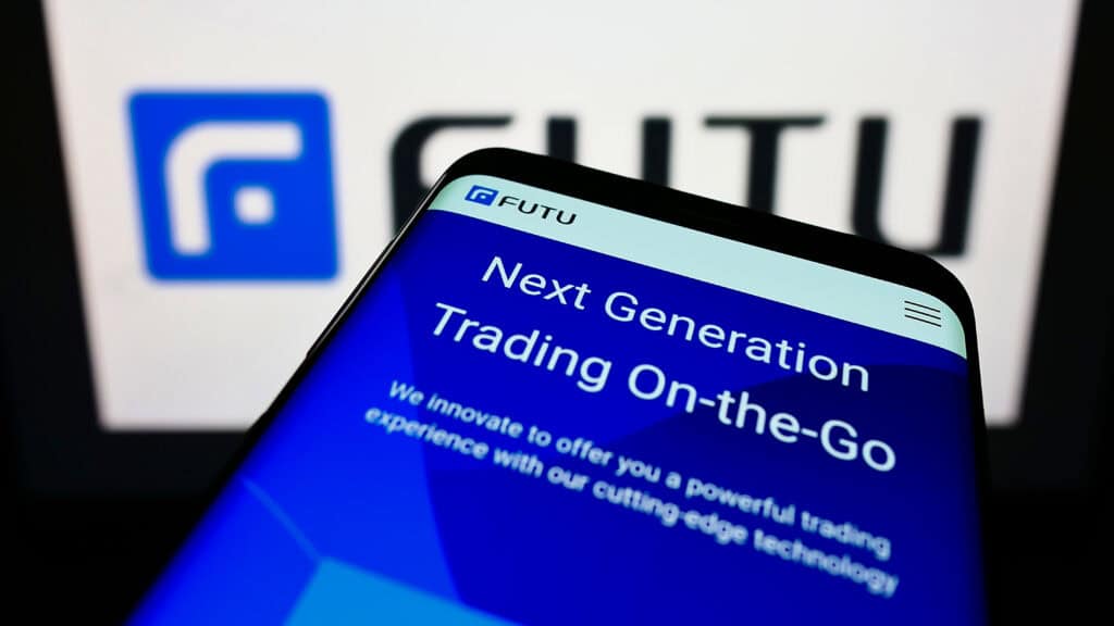 Person holding smartphone with website of Chinese brokerage company Futu Holdings Limited on screen with logo.